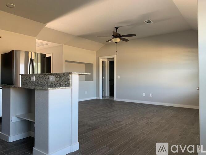 A spacious room with a ceiling fan and a counter with a backsplash.