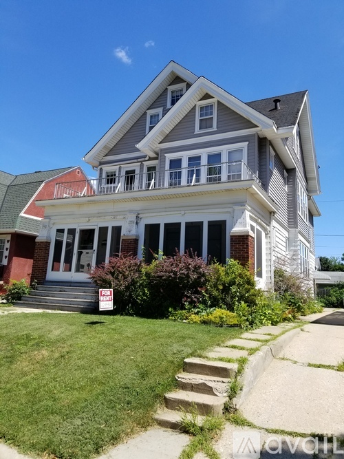 A house with a red roof and a sign that says "For Sale".