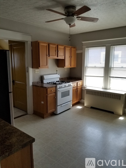 A kitchen with a refrigerator, stove, and cabinets.