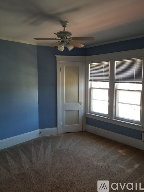 A room with a ceiling fan and a door leading to another room.
