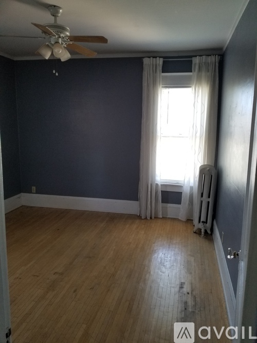 A room with a ceiling fan and a window with curtains.