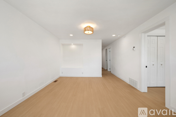 A spacious room with wooden flooring and white walls.
