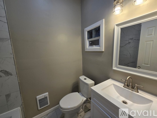 A bathroom with a toilet, sink, and mirror.