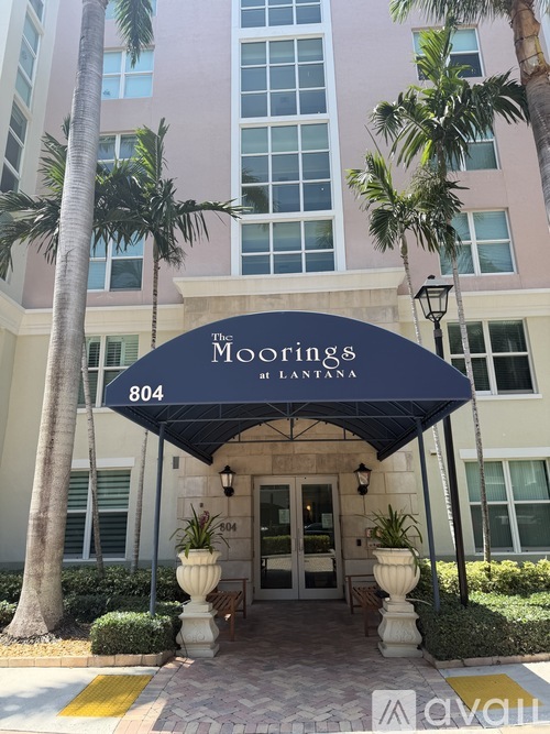 The Moorings at Lantana is a building with a blue awning and a yellow line on the ground.
