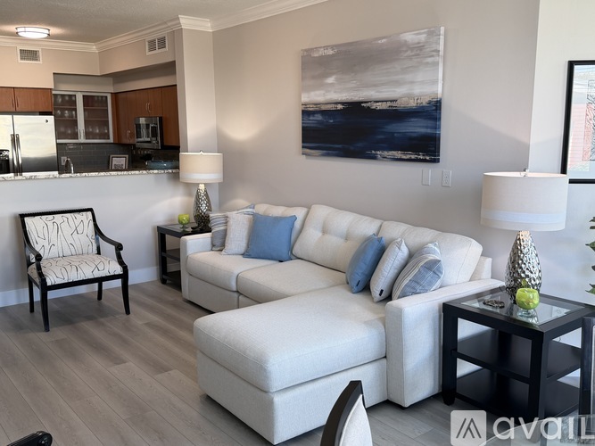 A living room with a white couch and a painting on the wall.