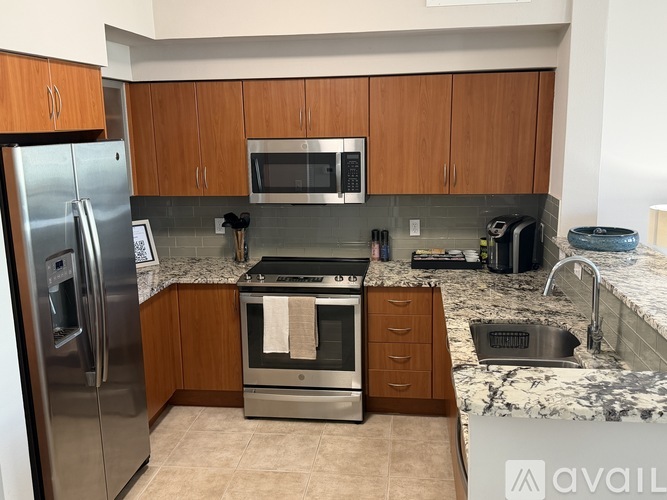 A kitchen with a refrigerator, microwave, oven, and sink.