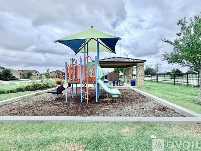 A playground with a green umbrella and a slide.