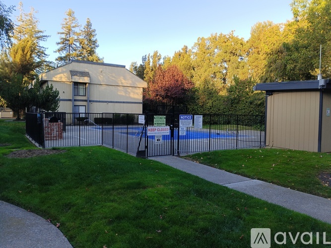 A building with a pool in front of it is surrounded by a fence.