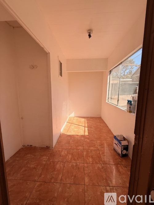 A room with a tiled floor and a window letting in sunlight.