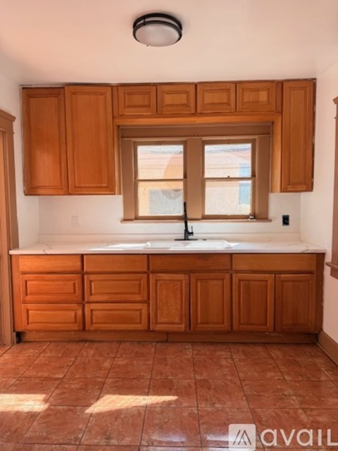 A kitchen with wooden cabinets and a tiled floor.