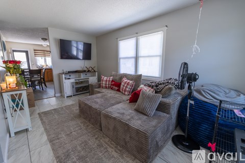 A living room with a grey couch and a television on the wall.