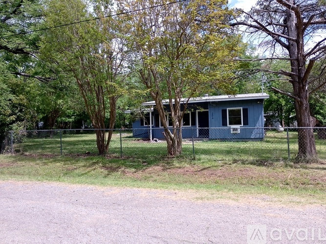 A blue house surrounded by trees and a fence.