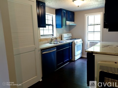 A kitchen with dark blue cabinets and white appliances.