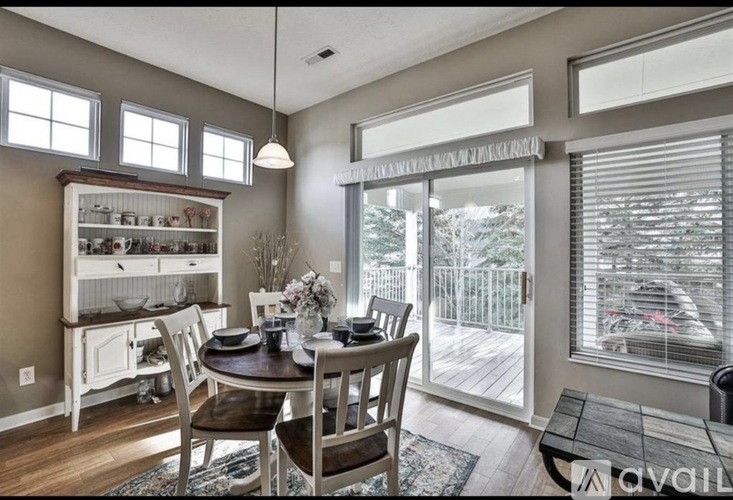 A dining room with a table set for two and a view of a deck outside.