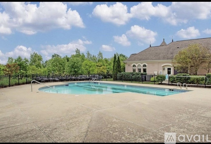 A large swimming pool in a backyard with a house and trees in the background.