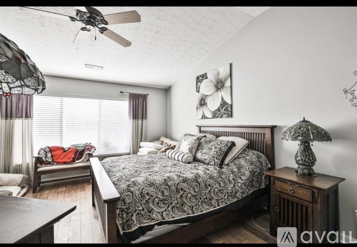 A bedroom with a large bed and a ceiling fan.