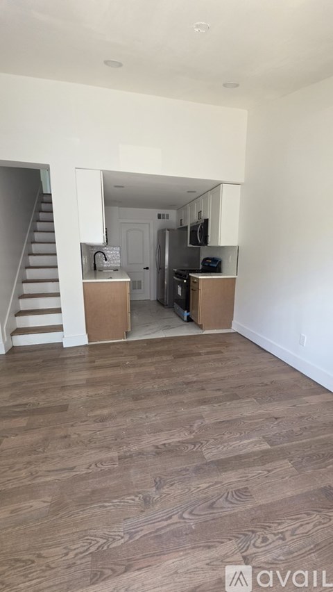 A room with wooden flooring and a staircase on the left side.