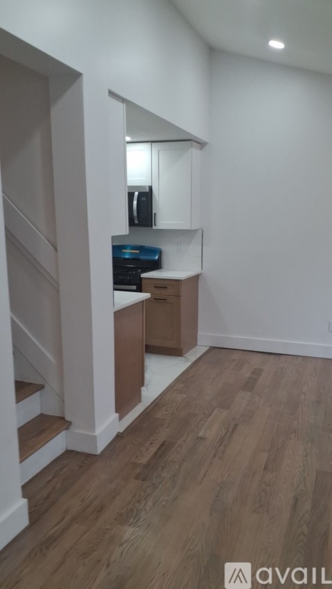 A room with wooden floors and a staircase leading to another room.