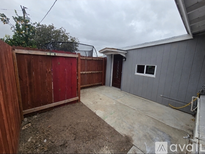 A backyard with a red fence and a grey house.