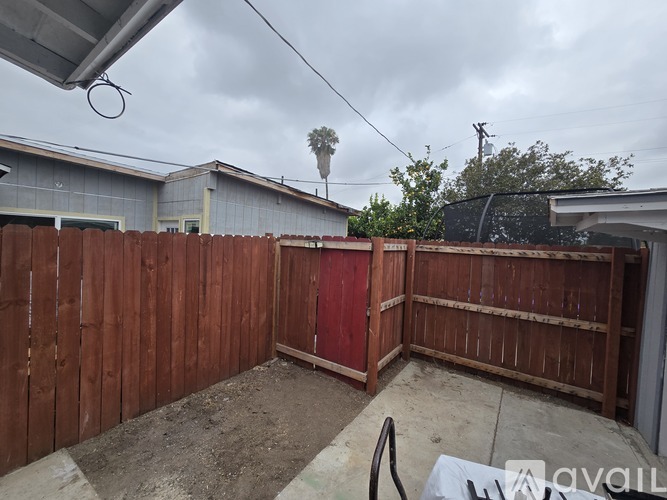 A backyard with a wooden fence and a red gate.