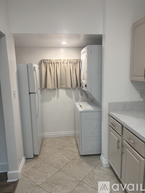 A kitchen with a white refrigerator and cabinets.
