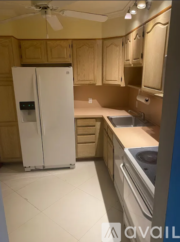 A kitchen with a white fridge and a fan on the ceiling.