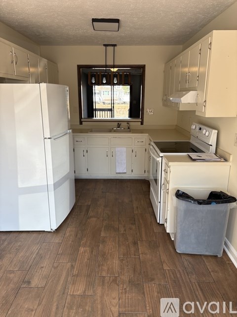A kitchen with white appliances and wooden floors.