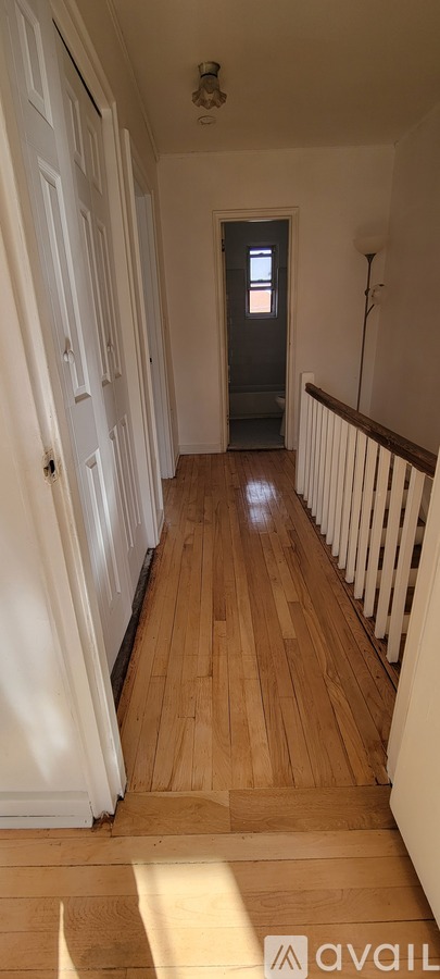 A hallway with wooden floors and white walls.