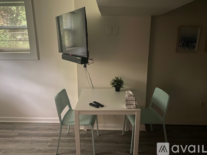 A white table with two chairs and a television on the wall.