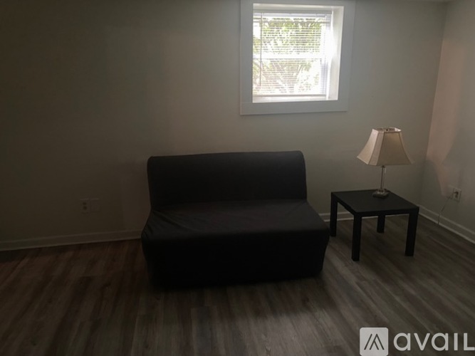 A black sofa sits in a room with a lamp and a table.