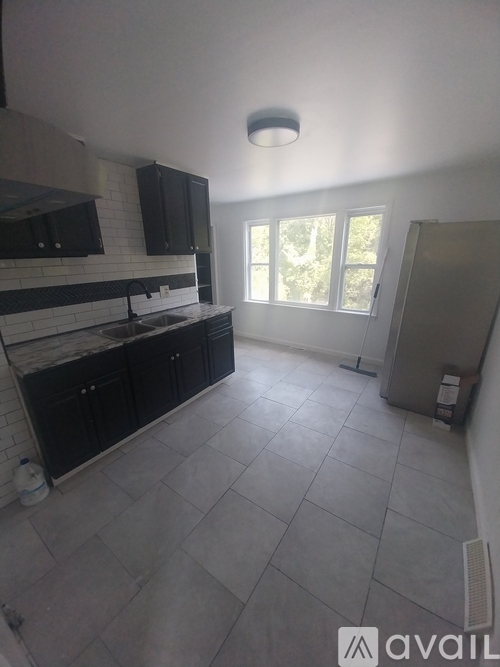 A kitchen with black cabinets and a tiled floor.