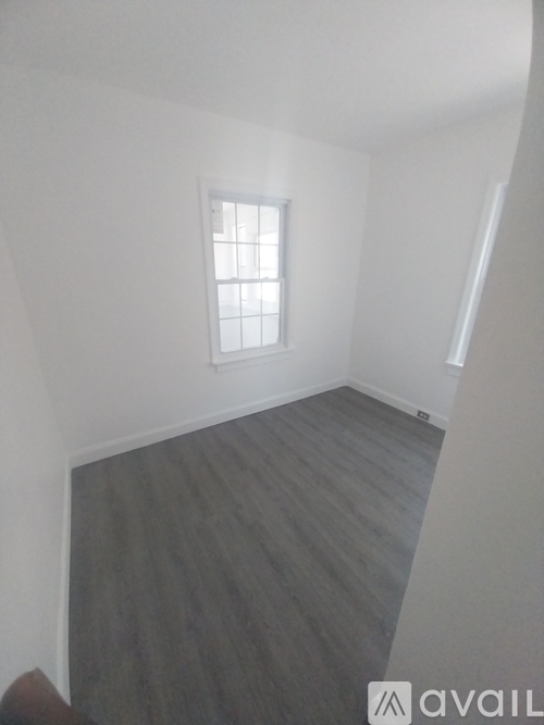 A room with a window and wooden flooring.