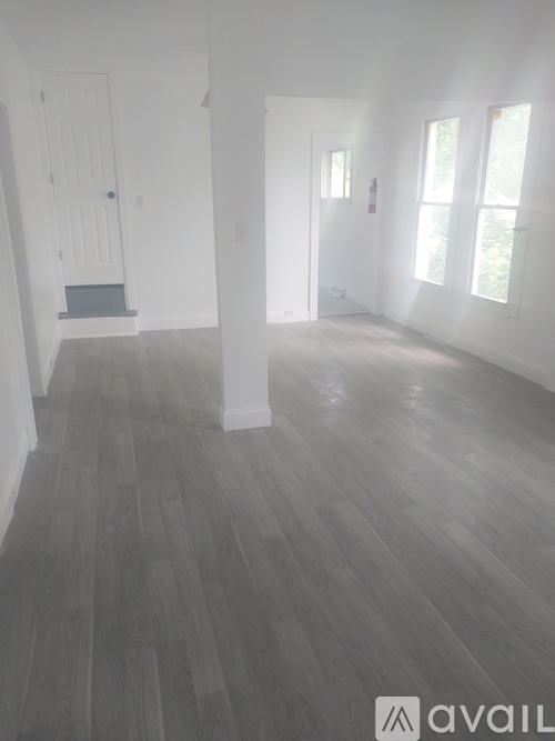 A room with wooden flooring and white walls.