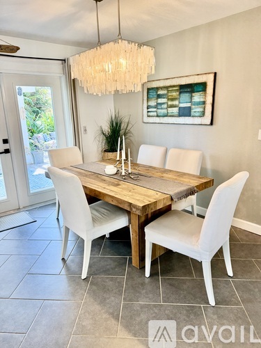 A dining room with a wooden table and white chairs.