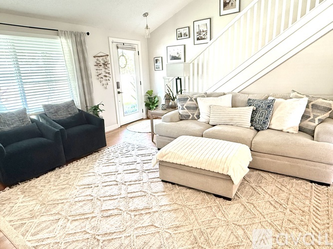 A living room with a couch, chair, ottoman, and a rug.