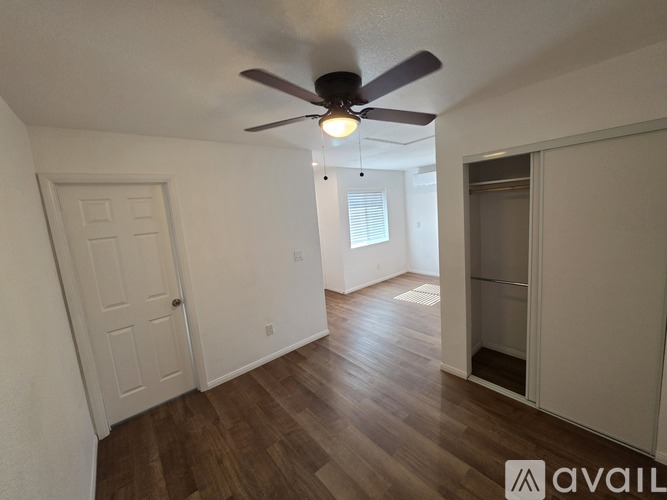 A room with a ceiling fan and wooden flooring.