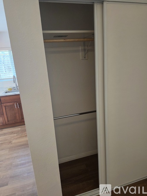 A white closet with a shelf and a white door.