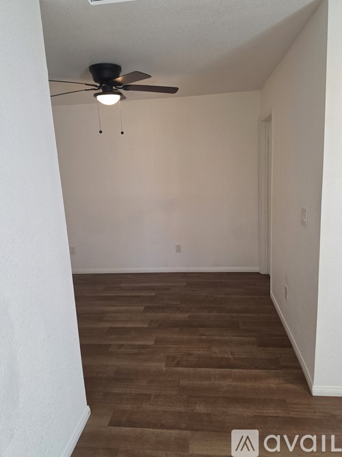 A room with a ceiling fan and wooden flooring.