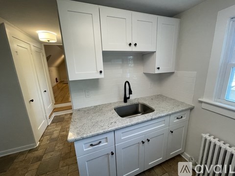 A kitchen with white cabinets and a granite countertop.