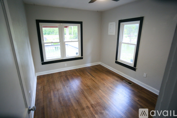 A room with wooden floors and two windows.