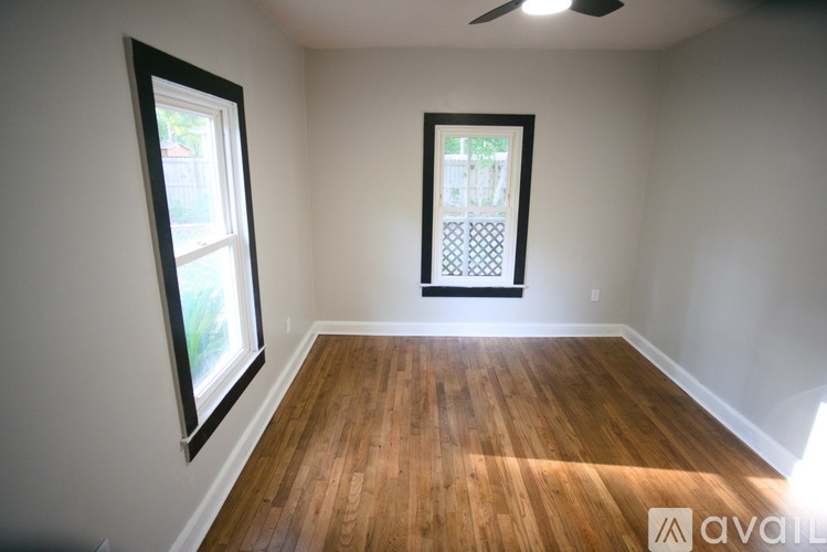 A room with wooden floors and two windows.