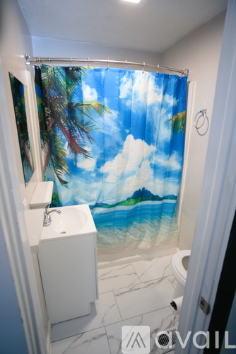 A bathroom with a shower curtain featuring a tropical scene.