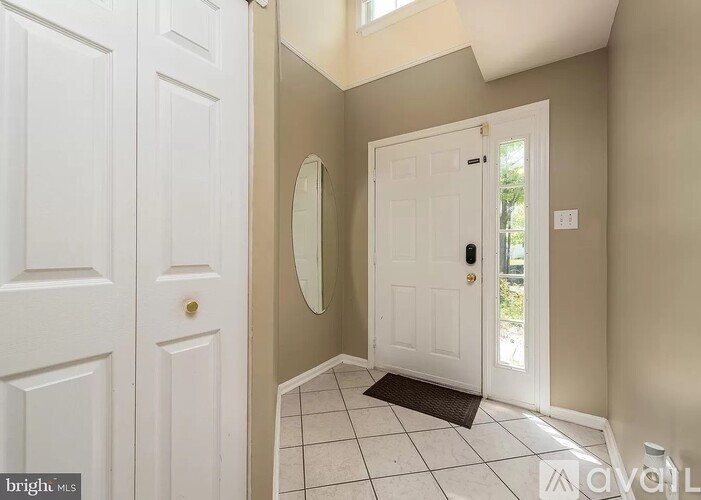 A white door with a mirror above it in a hallway.