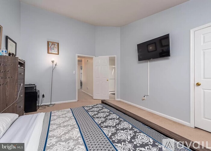 A bedroom with a bed, a television, and a wooden dresser.