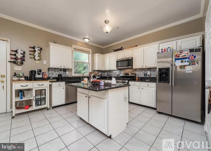 A kitchen with white cabinets and a black countertop.