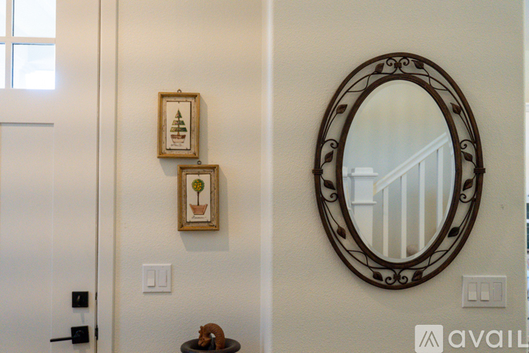 A mirror with a decorative frame hangs on a wall above two small framed pictures.
