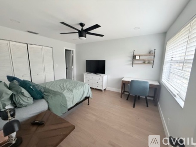 A bedroom with a bed, a chair, and a ceiling fan.