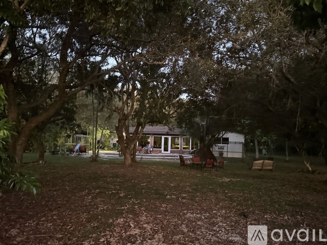 A house is surrounded by trees in a grassy area.