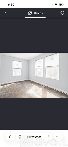 A room with a wooden floor and three windows.