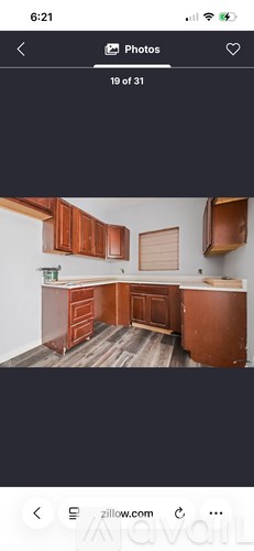 A kitchen with wooden cabinets and a white wall.
